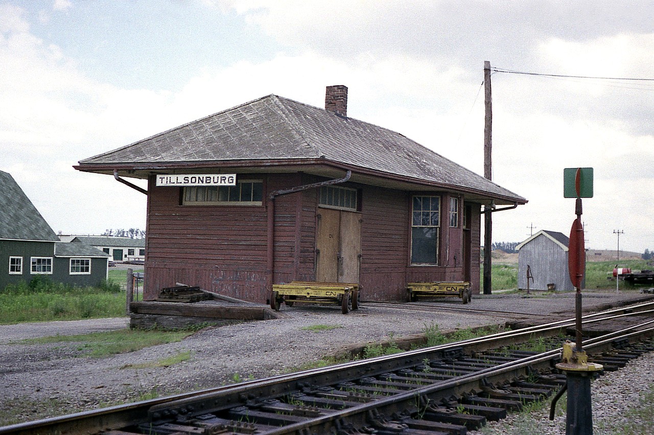 This station used to sit by former Hwy 19 just south of hwy 3 at Tillsonburg. It has been replaced by a modern MoW building. In this photo the old building appears to be in use for motor car storage and tool house. Wonder how many years it has been since it last experienced a passenger train?
Photo taken with Hwy 19 to my back. Station was on the north side of rails. To this day, the switch is still there and so is the pole!