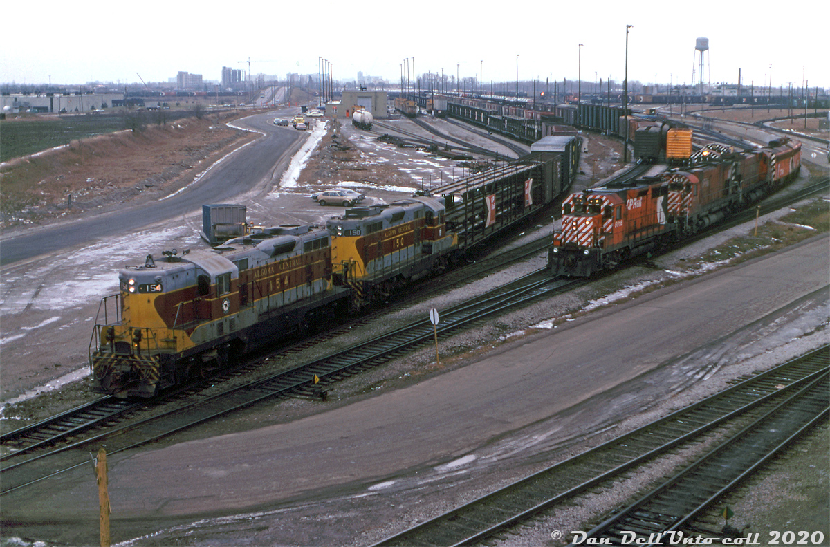 For a period in 1978-1979,  CP had Algoma Central GP7's 150 and 154 on lease (both part of ACR's first GP7 order built in 1951). They mostly ran out of Toronto on various road and local jobs. Here, the pair head up CP's Couboug Turn, getting ready to leave Toronto (Agincourt) Yard at the north-east end by Finch Avenue, in order to head down the connector and join the Belleville Sub at Staines. No shortage of open trilevel and bilevel autoracks are in today's train, likely bound for the GM plant in Oshawa.

Power on the adjacent track (possibly heading to/from the diesel shop in the distance) includes CP GP35 5016, M630 4510, another big M and an A-B pair of F-units. Two Alco/MLW switchers wait behind, likely pulldown power that worked the east end of the yard doing flat-switching. The old van shop is visible in the background.

Keith Hansen photo, Dan Dell'Unto collection slide.
