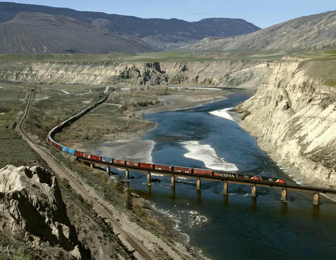 Eastbound train 416, intermittent traffic Port Mann to Edmonton, crosses the Thompson river east of Ashcroft. CP main is on the left. CN predecessor Canadian Northern made several crossings of the river as earlier constructed CP built on the most stable side .