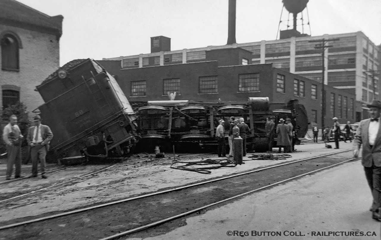 Mid day on May 27, 1953 finds CNR E-10-a 2-6-0 Mogul 88, the lead locomotive on a double headed freight up the mountain, tossed on her side at the intersection of Ferguson Avenue and Rebecca Streets in Hamilton.  This derailment was caused by the lead wheels of 88's tender picking the switch of the Rebecca Street spur, jackknifing the engine causing it to flip.  The three crew members onboard; Engineer Charles Penfold (jumped clear), Fireman Richard Day, and head end Brakeman Murray Calder, all escaped with minor injuries.  The tender has been partially righted in this image, and is supported by timbers after having made contact with the Alexanian Oriental Rug Cleaning Company building.  The trailing 3506 followed 88 down the spur stopping short of the yard engine working nearby industries.  After 3506 and the rest of the train returned to Hamilton Yard, a steam wrecking crane was brought in to clear the mess.CNR 88, built as Grand Trunk 1008 by CLC in 1910, renumbered GTR 910 in 1919, CNR 910 in 1923, and CNR 88 in 1951.  After this wreck, which cracked the crown sheet atop the firebox, 88 would be sent to Stratford for repairs.  Retired in 1957, she would be placed on display as GTR 1008 just east of Morrisburg, Ontario along Highway 2 near the Upper Canada Pioneer Village.  Along with it sits the historic Aultsville train station and two GTR coaches.  CNR S-1-g Mikado 3506, built by CLC as GTR 486 in 1917, would be scrapped just over 4 years later in July, 1957.