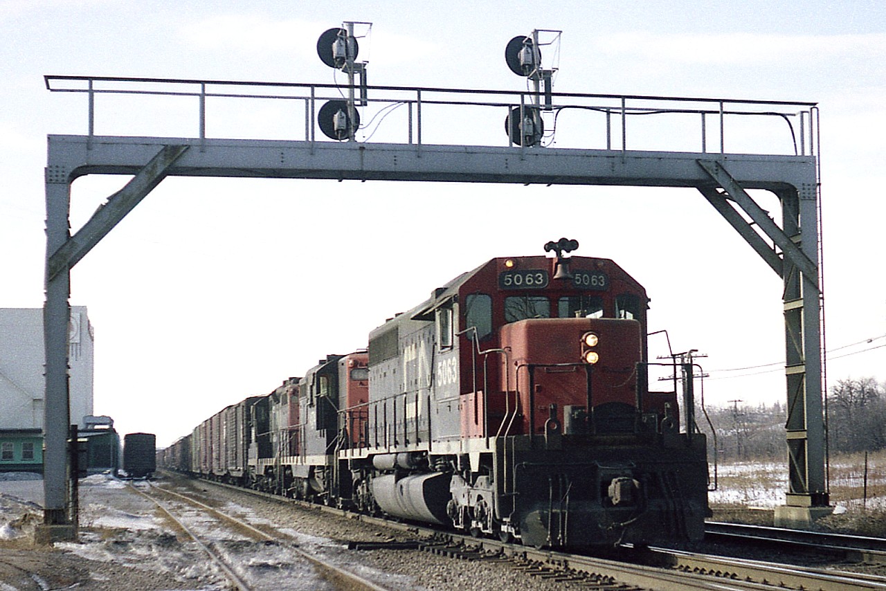Rolling eastward under the old signal bridge that used to be almost beneath the Waterdown Rd overpass, is CN 5063, 4574 and 4560. Note a car in the siding at the Kirkelder Spray Mister building, known in recent times as the Aldershot Cold storage, until its demise about 10 years ago. Lead unit was sold and re-manufactured for service on the BNSF in 1999. The trailing GP9s went for CN rebuilding and renumbering by 1993.