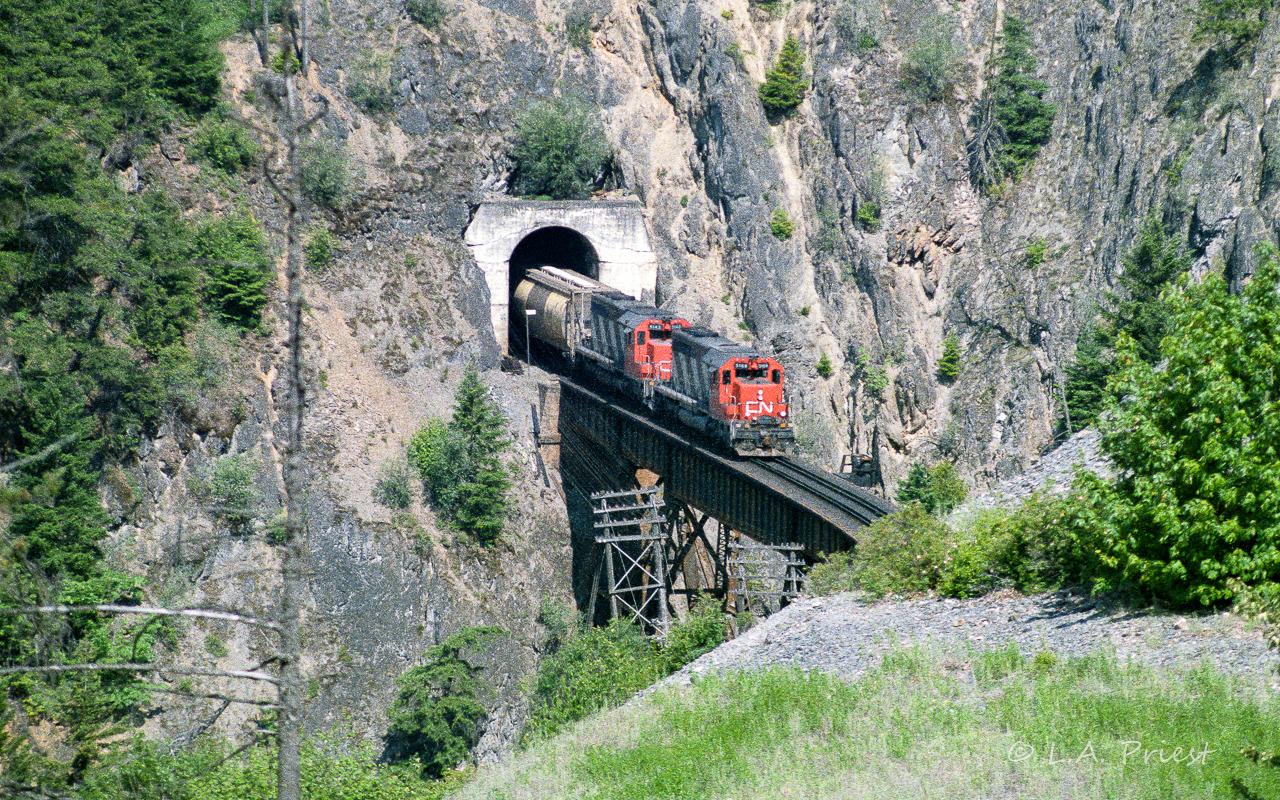 The 5166 and 5143 have just come out of a hole in the wall onto a short bridge. There is only 5.5 miles left to Boston Bar and the crew will enjoy a break waiting for their return ride to Kamloops. The mile board at the tunnel exit reads 120. Pretty certain of the year, month could be June or July.