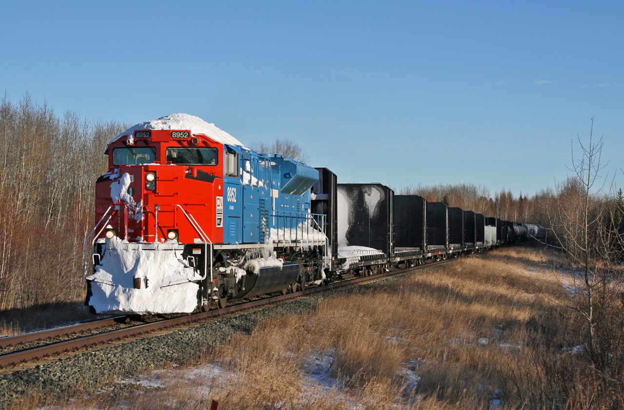 After battling a significant winter storm on the prairies and being stuck due to heavy winds east of Biggar, CN 8952 is still covered in ice and snow.  The storm did not affect the Edmonton area and here we see M 34791 10 rolling through the country side in Lobstick, Alberta after meeting Q198 at Evansburg.
