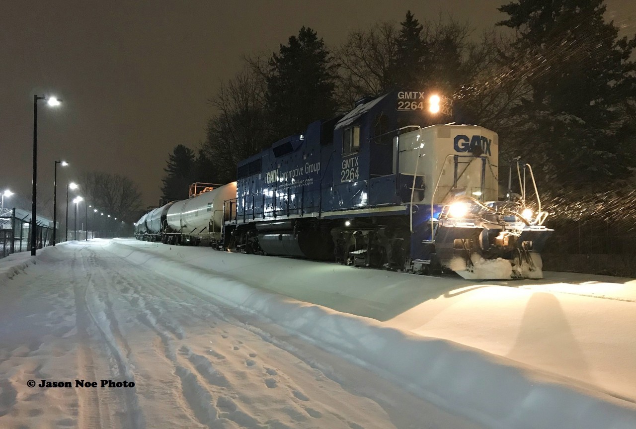 In a snow storm, CN L566 with GMTX 2264 waits near Roger Street in Waterloo, Ontario to head north to Elmira on the Waterloo Spur with six tankers. They were waiting to proceed on the shared portion of the ION Light Rail network, however a faulty switch ended L566's night early and they eventually proceeded back to Kitchener.