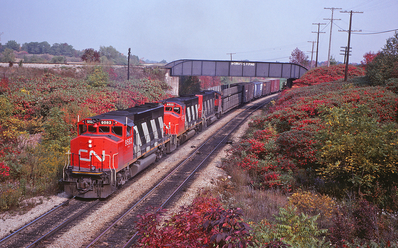 After admiring David Vincent's fantastic over/under catch from New Year's Eve, I realized I had a shot with a similar angle in my slide collection. Here is a "before" shot from October 1979, of CN #387 making its way to Sarnia. That's a GTW open autorack behind the power, followed by a Missouri Pacific 60' auto parts boxcar.

There are quite a few changes to note over the past 41 years - obviously the sumac thickets have given way to young trees. Clearly the bridge has not been painted in that time, since that one line of vulgar graffiti was there in '79 and is still there today.