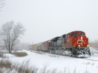 CN 8889 leads a 144-car CN X306 through a snowstorm as it rounds a curve. BCOL 4651 is acting as DPU.