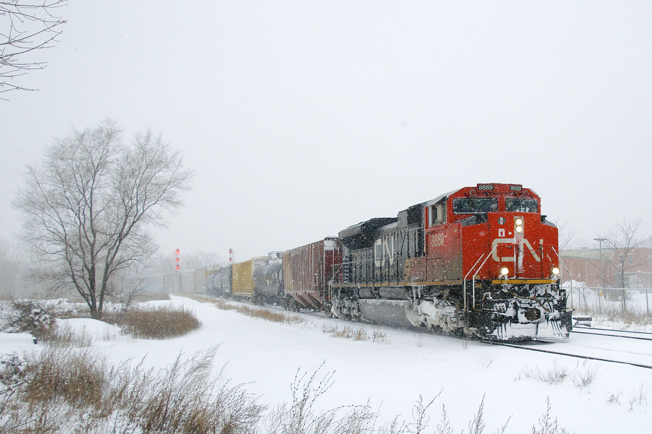 CN 8889 leads a 144-car CN X306 through a snowstorm as it rounds a curve. BCOL 4651 is acting as DPU.