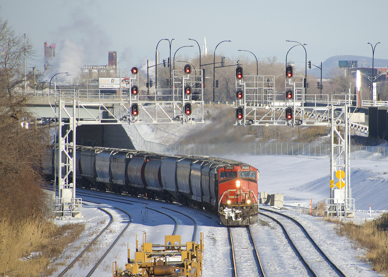 Empty grain train CN 875 has just left Turcot Ouest with a new crew onboard as it passes underneath a pair of signal gantries. This train has CN 2532 up front, CN 8883 mid-train and 187 cars.