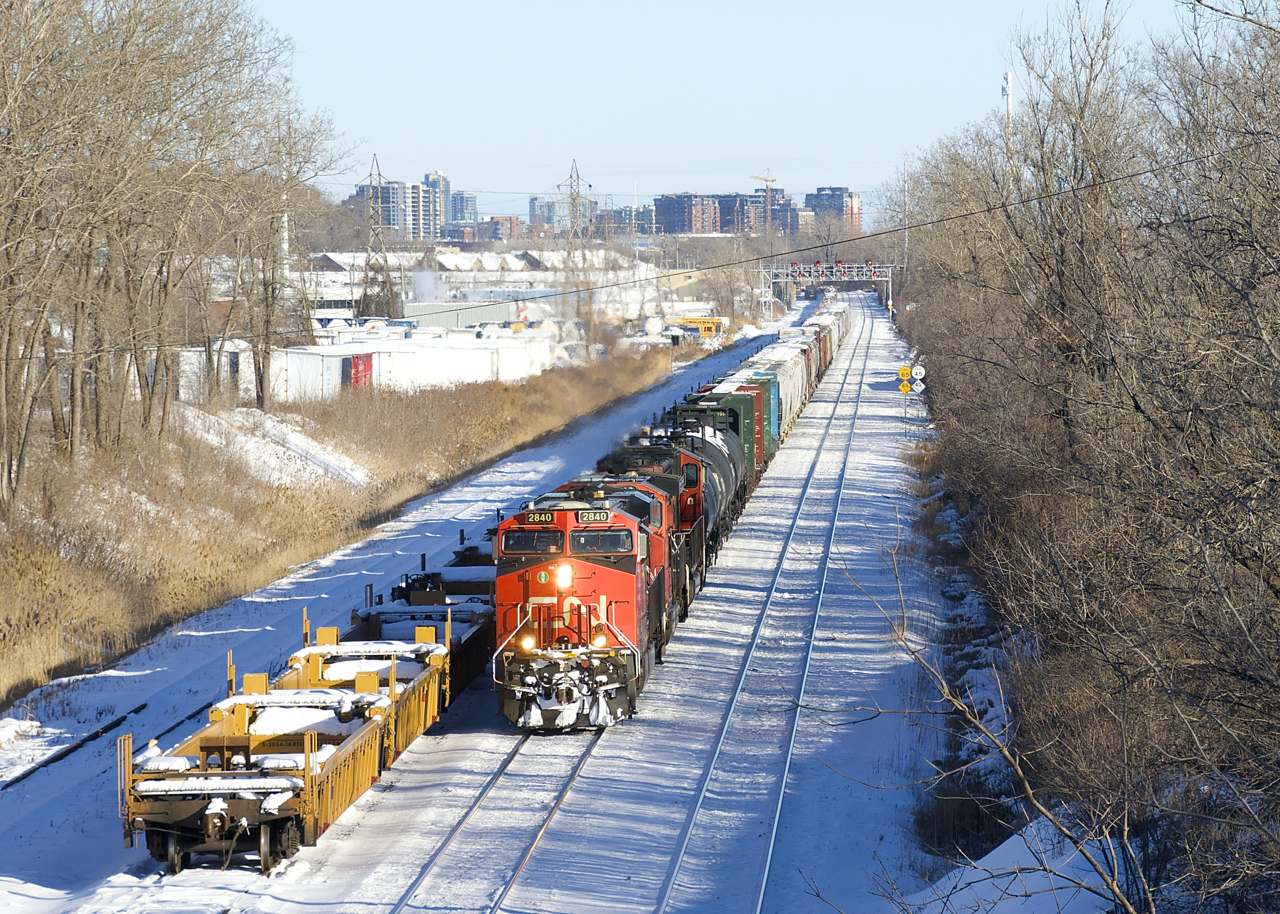 CN 527 is passing stored well cars on the freight track of CN's Montreal Sub as it approaches Taschereau Yard. Power is CN 2840, CN 2500 & CN 5600.