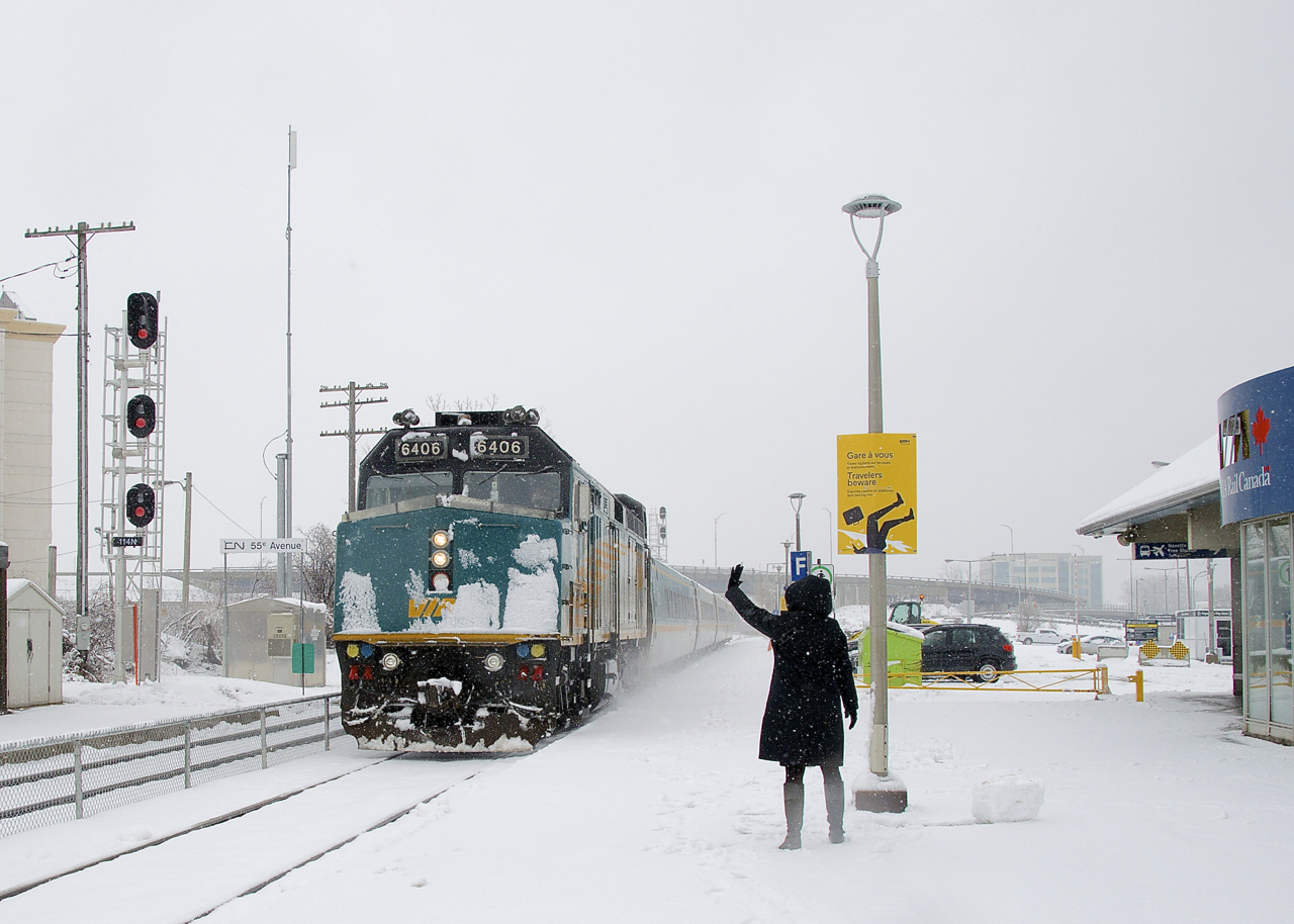 A station attendant greets VIA 67 as it arrives at Dorval Station towards the end of a snowstorm. She is taking a break from building a snowman; seen at bottom right.