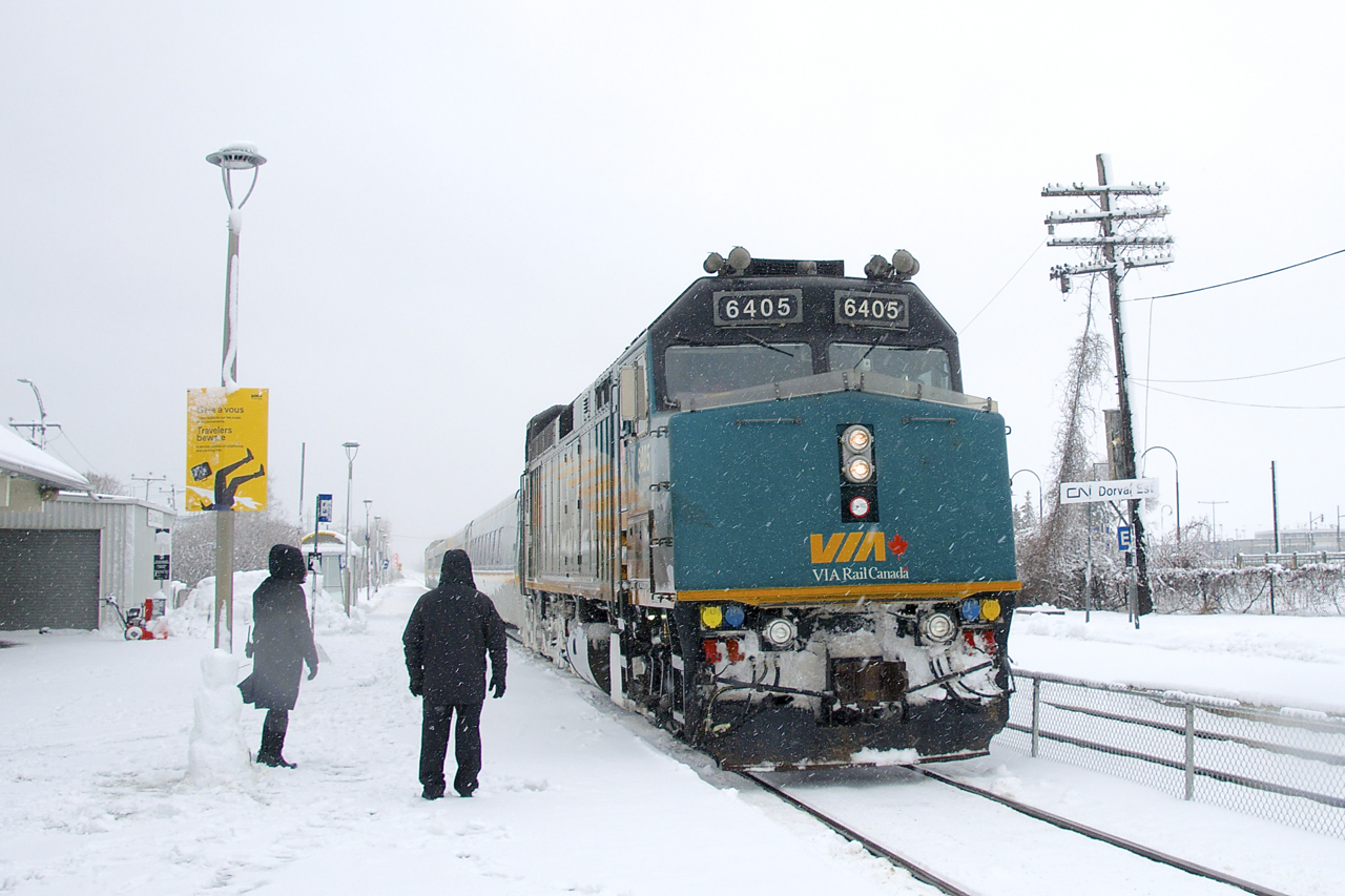 A pair of station attendants have just completed a snowman as they greet the arriving VIA 62 at the end of a snowstorm.