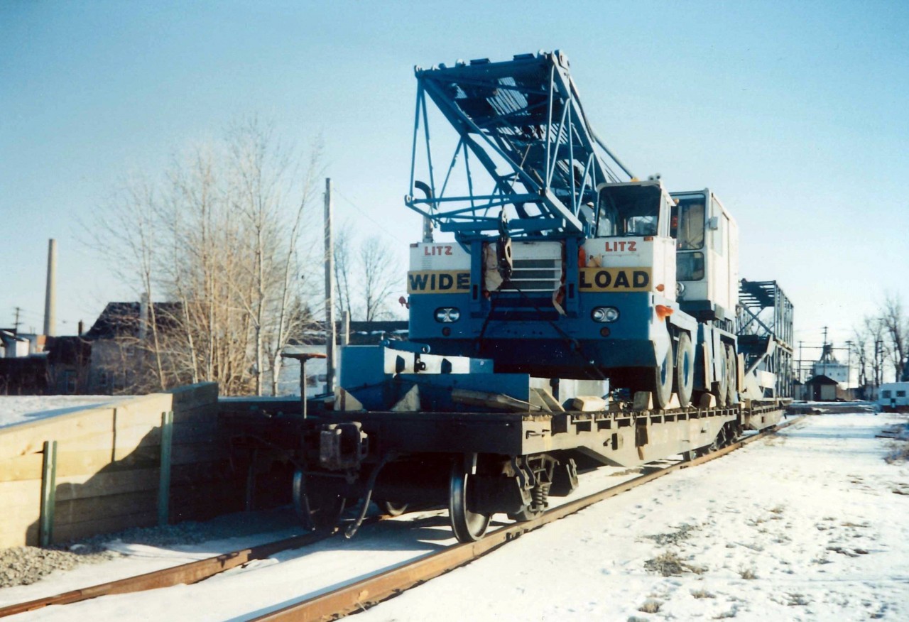 With the removal of the Downtown Spur (opposite to the King. St. CNR Station), CN invested in a new loading dock on the East Side of town that utilised the remnants of the former Welland Railway tracks (north-south) that dead ended just north of Bridge #20.  The Unloading Dock was rarely used, but on this day it has received two (2) flat cars of equipment.  In the background you can see a lake ship (right), and INCO Chimney (left).  The tracks were removed in the late 90's, the loading dock remains as an odd reminder that the rails once went through here.