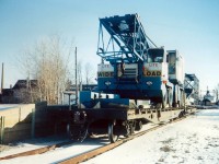 With the removal of the Downtown Spur (opposite to the King. St. CNR Station), CN invested in a new loading dock on the East Side of town that utilised the remnants of the former Welland Railway tracks (north-south) that dead ended just north of Bridge #20.  The Unloading Dock was rarely used, but on this day it has received two (2) flat cars of equipment.  In the background you can see a lake ship (right), and INCO Chimney (left).  The tracks were removed in the late 90's, the loading dock remains as an odd reminder that the rails once went through here.    