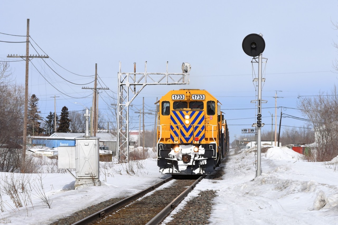 Englehart to North Bay train 214 does track speed through New Liskeard Ontario on its way Southbound towards headquarters. A deactivated GRS mast and cantilever still stand which once stood guard over a switch for a since removed siding.