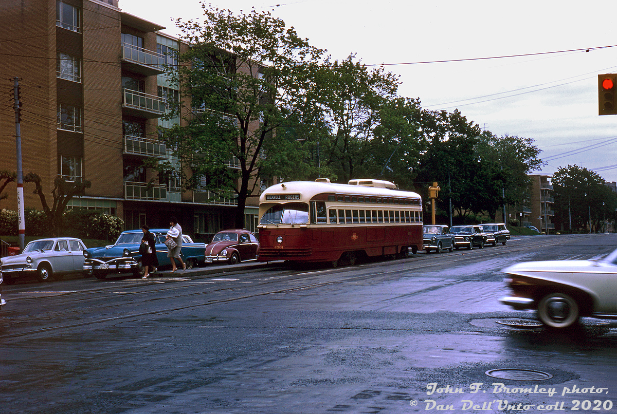 A wet and gloomy day finds TTC PCC 4561 (an A9-class ex-Cincinnati car built by St. Louis Car Co. in 1947) pausing with traffic at the light westbound on St. Clair, after letting off two ladies on the streetcar island at Spadina Road. The PCC is operating on the Rogers Road route, taking St. Clair westbound to Oakwood, and heading north to Rogers and on to Bicknell Loop.

Throughout the 1960's when it became known Toronto was planning to phase out its streetcar network by 1970-ish, local transit photographers such as John Bromley and Robert McMann travelled all over Toronto photographing streetcars in various places around the network, and groups such as the UCRS held fantrips with streetcars travelling over all parts of the system and routes that would be replaced by new subway lines (the Bloor-Danforth subway opening in 1966 and 1968 nixed a bunch of streetcar routes).

While Toronto in the early 1970's ultimately decided to keep its streetcar fleet, some routes were replaced by buses, and the last Rogers Rd. cars would run in July 1974 before replacement by the Route 63F branch of the Ossington trolleybus. The 4500-series St. Clair Carhouse based PCC's such as 4561 would continue to serve the route into its final days.

John F. Bromley photo, Dan Dell'Unto collection slide.