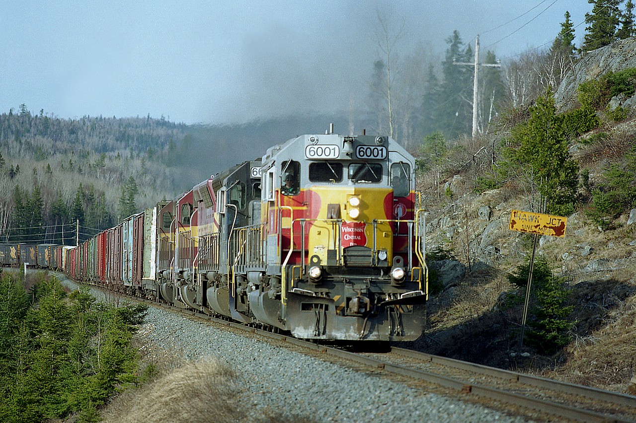 A really enjoyable destination back in the mid '90s was to pack the car and head to Wawa, Ont. The Algoma Central, while rather out of the way, was really worth the trip. Times were good, trains relatively plentiful and certainly worth going after. But it all came crashing down once CN took over Wisconsin Central (2001), which in turn had taken over Algoma Central back in 1995.
I made several trips. In 1996 to capture the last of AC paint before it all became WC power. And in 1998 when
I heard the Sinter Plant in Wawa was closing, effectively ending most of the rail activity in the area.
Last time I was there at Hawk Jct was Sept 2020, and it was a ghost town.
Pictured here is a typical afternoon southbound, heading for Sault Ste. Marie with mixed freight.  Head end power consisting of WC 6001, 6639, 6582 and 6627 is thundering up the steep grade out of Hawk Junction. The power, the scenery, and the genuine thrill of a chase made this one of my favourite destinations back then.