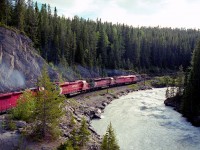 Heading westbound along the Kicking Horse River in June 1990 after a crew change in Field, BC., CP 9000, a two year old SD40-2F is leads eight locomotives and a long train.