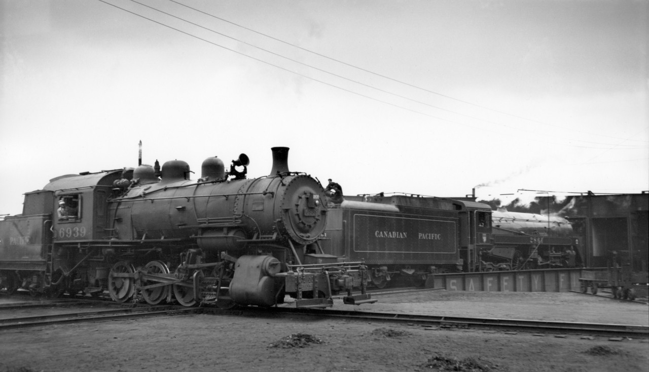 Switcher 6939 passing by in front of 2861 on turntable at Drake street roundhouse