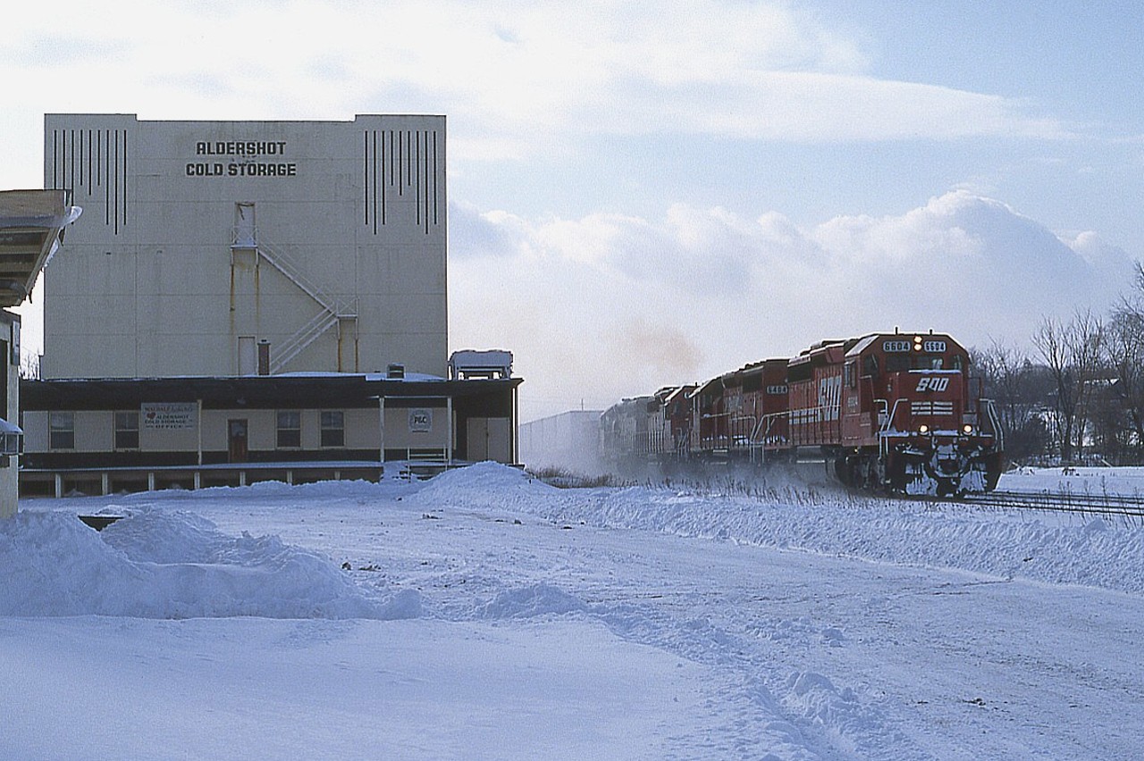 Snowstorm over, skies clearing.  I'm down in the parking area of the old FX building and cold storage parking area and grabbed a shot of an eastbound CP moving along at a good clip. I've only recorded the first two units, SOO 6604 and 6404. I guess my pen must have froze up. :o)
Cold storage plant demolished 2009. And CP no longer uses CN track to get to Toronto.