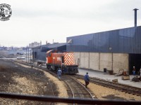 Taken from the cab of SW8 7170 (GMD, 1951) on the CN Guelph Yard job, a meet is seen with the CP yard job, led by S3 6529 (MLW, 1955). CP is seen proceeding up the grade from Dawson Road towards Maple Leaf Mills, today Traxxside Transloading. At this time the facility only had <a href=https://guelph.pastperfectonline.com/photo/972F4526-25F7-49EC-B62B-041912931174>one spur on the property.</a>  CN 7170 sits clear of the South Industrial main on the lead to National Standard; today Traxx 5 and 6; the Traxxside glass tracks. Both locomotives would be off the roster by 1986. The facility pictured behind is Court Galvanizing Ltd.