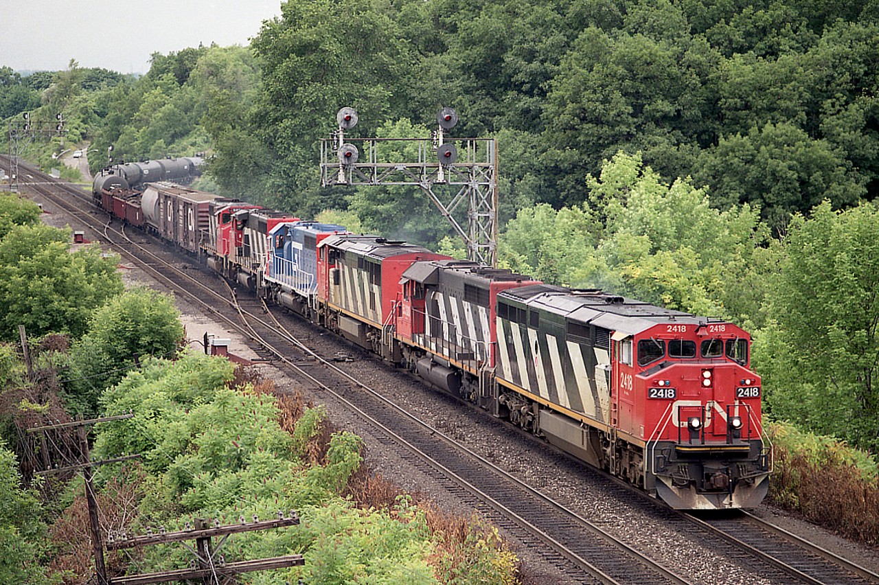 One of those nice bright overcast type days that I enjoy; and even better when a decent looking train comes along. I'm on the "railfans" walkbridge on this occasion; and off the hill comes CN 2418, 5030, 2416, GT 5936, CN 9510 and 9400 leading this Sarnia to Toronto-bound train. Don't remember if it was hot and muggy, but it sure looks it. Image shot using 120 medium format roll film in a Mamiya Pro 645.