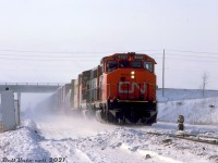 CN GP40-2L(W) 9401 and a sister unit kick up a cloud of snow as they head eastbound on CN's York Sub with a freight in tow, passing under the Keele Street overpass by the Mile 24 marker on the approach to Snider. The name "Snider" comes from a few early families in the area that owned farmland and mills in what was once the community of Edgeley (Jane & Hwy 7) in the 1800's.<br><br><i>Bill McArthur photo, Dan Dell'Unto collection slide</i>.