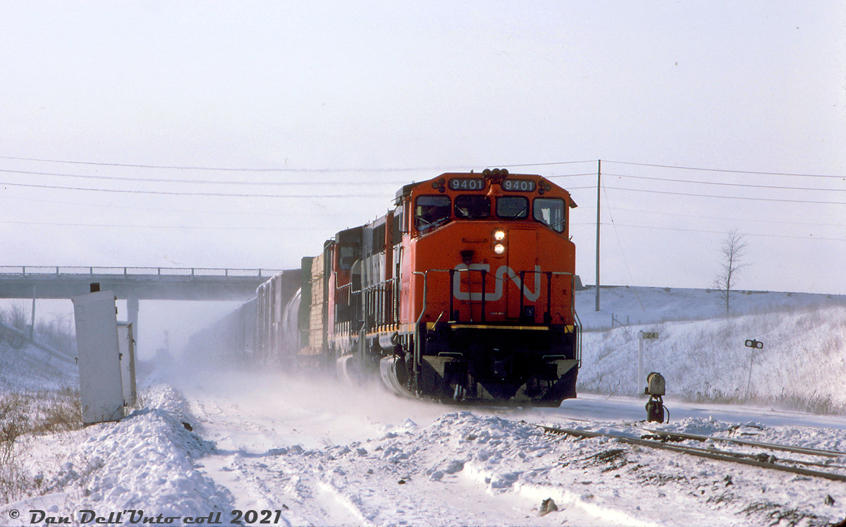 CN GP40-2L(W) 9401 and a sister unit kick up a cloud of snow as they head eastbound on CN's Halton Sub with a freight in tow, passing under the Weston Road overpass by the Mile 2.4 marker on the approach to Snider West. The name "Snider" comes from a few early families in the area that owned farmland and mills in what was once the community of Edgeley (Jane & Hwy 7) in the 1800's.

Bill McArthur photo, Dan Dell'Unto collection slide.