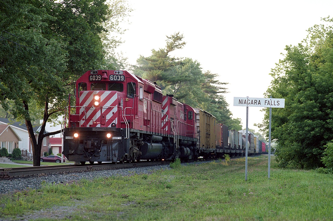 As I have mentioned quite a few times before, Niagara Falls was one of my favourite places to shoot trains. It always puzzled me that very few others shared this view. Probably one of the factors was most of the trains ran either late day or under darkness.
This example was shot just before it would have been too dark due to all the foliage to get a decent shot. Sunset was not far off.  CP 6039 and 4248 have just crossed the border and are seen at mile 1 rolling along parallel to Palmer Av in the falls. On approach to Clifton Hill.  I have wondered too if there were any surly engineers who took great delight in tying up all the tourist traffic with their 60+ car trains. Hope not. But then, it couldn't be helped.  (This rail line was pulled up in 2000)