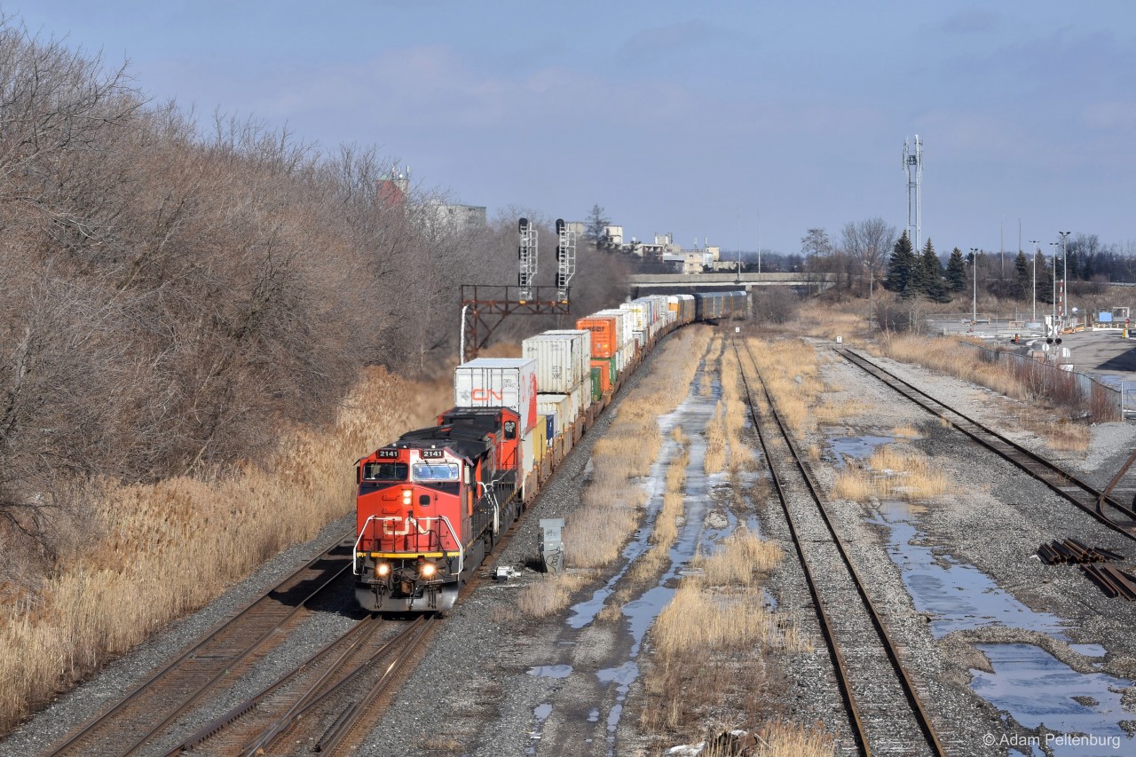 CN 2141 clatters across the turnout as it approaches Oshawa from the east. The train is E271, which predominantly handles automobile traffic but as seen here can also pull containers from time to time. Over the last few months CN has been putting an unusually high number of these endangered Dash 8 locomotives in the lead of trains on the Kingston Subdivision, and I'll continue to take full advantage of that while I can.

The pair of tracks on the right were once part of a yard that occupied all the open space between the mainline and the track furthest right. It's largely disappeared over the last few years with the closure of the Oshawa GM plant, but it was usually empty for nearly a decade prior to that. Now that it's been announced that Oshawa GM will be reopening, it's hard to say whether this yard and the others scattered around the plant will be used again. I hope that's the case, or at the very least I hope I get to photograph some new automotive trains here in the future.