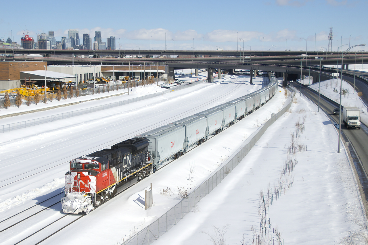 Snow-covered CN 8894 is the leader on CN 875 as it approaches Turcot Ouest, where it will get a new crew. IC 2707 is mid-train on this 218-car long empty grain and potash train.