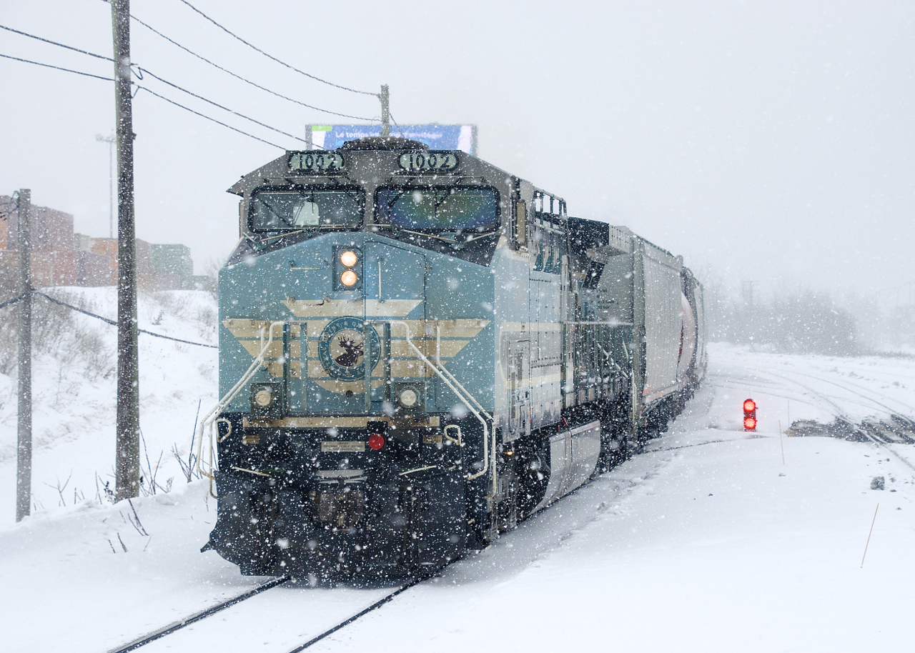 Thick snow is falling as CEFX 1002 brings up the rear of CP 112. After yarding the intermodal portion of its train in Lachine IMS Yard, the head end and mid-train power went light to pick up autoracks and grain cars from the tail end of the train, which had been left on track three of the Vaudreuil Sub.