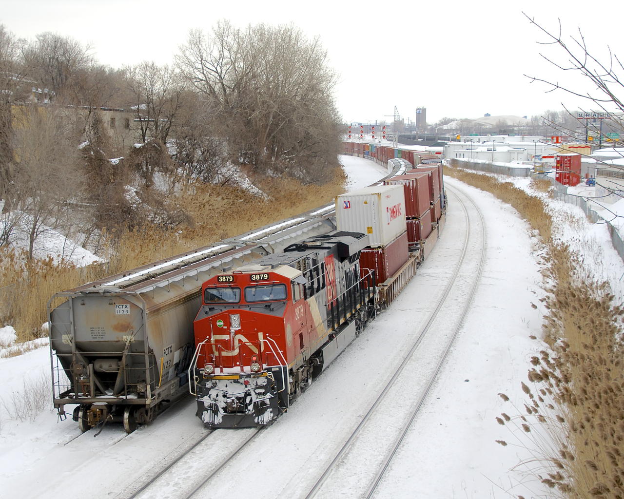 CN 100 unit CN 3879 brings up the rear of CN 120 as it passes a small cut of grain cars.