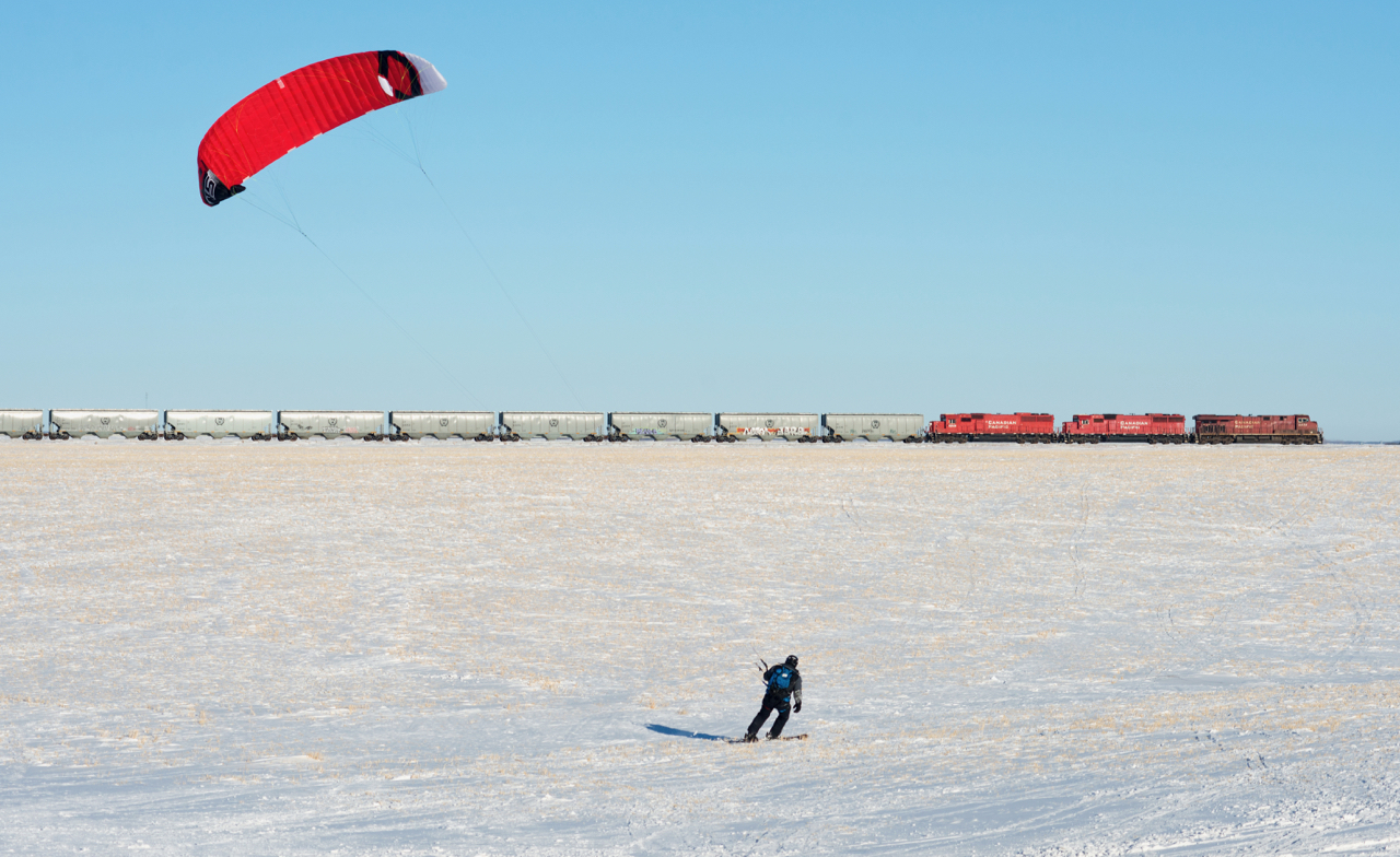 On a cold and clear winter evening, a second CP N08 makes it's way south toward Regina.  In the foreground, a kite skier makes great use of the snow covered fields and endless Saskatchewan winds.
