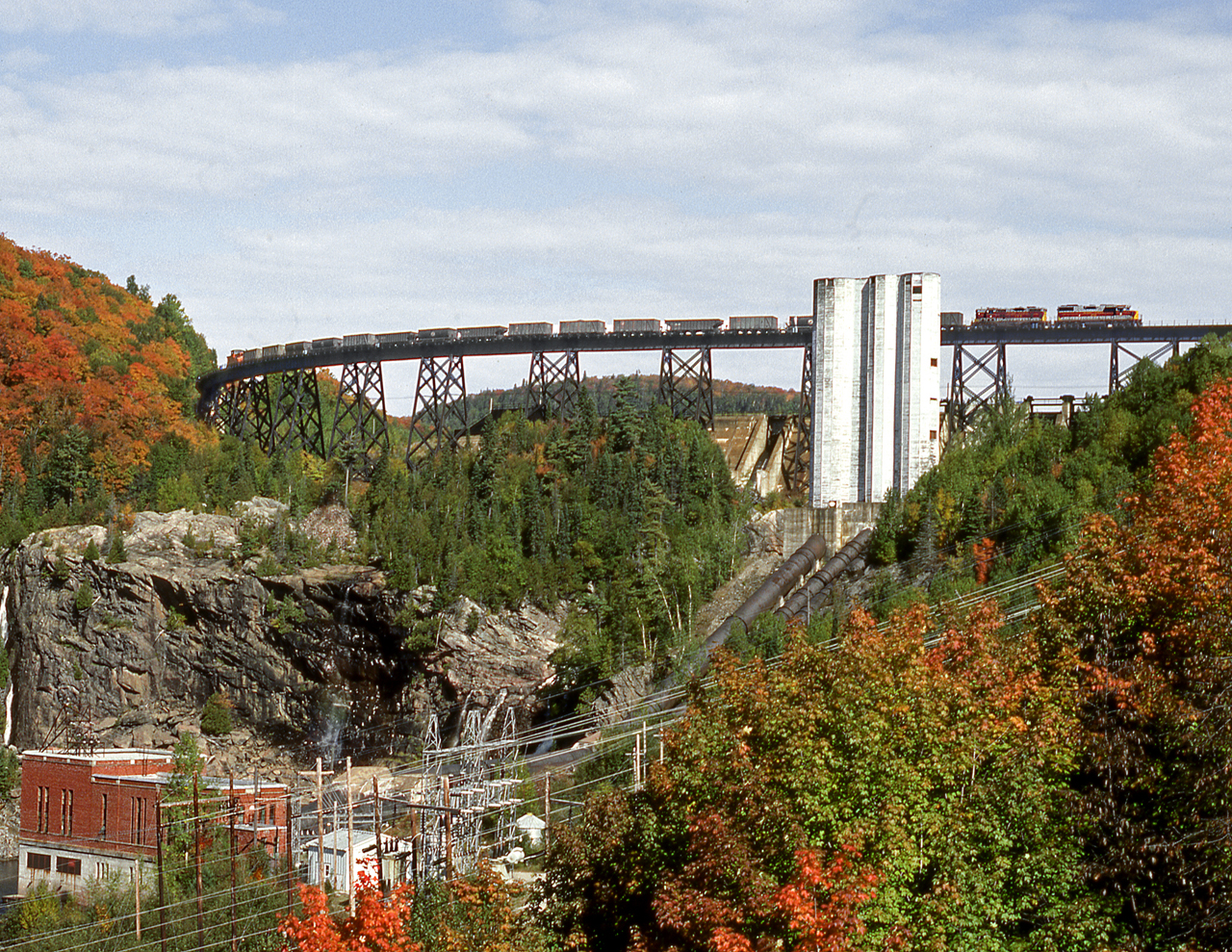 A southbound sinter train crosses the bridge over the hydro-electric dam on the Montreal River. A previous derailment backed tonnage up allowing for a rare daylight run of an ore train.