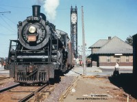 In response to <a href=http://www.railpictures.ca/?attachment_id=44074>Arnold’s 1975 image</a> facing west, I offer this 1955 view facing east.  CNR K-3-a Pacific 5567 leads train M219, the evening Fort Erie-Stratford mixed, on its 114.9-mile journey home.  Baggage carts are positioned at the ready with the handler at work.  The stop at Port Colborne is scheduled as 1655h.  Trains M218/M219 operated daily except Sunday running Stratford-Brantford-Fort Erie, departing Stratford at 0715h arriving Fort Erie at 1225h, and returning from Fort Erie at 1615h to Stratford at 2125h, each train laying over at Brantford for about 45-50 minutes to meet mainline trains.  CNR 5567, a Grand Trunk Railway product of 1912, originally P4 class number 231, renumbered in 1923 to 5567, would be scrapped in May 1958.  Welland Canal bridge 20 (built 1929 for the 4th canal) stands tall in the background as it did for 68 years until removal in 1997.  Bridge 21 (Clarence Street) remains in service immediately to the south (92 years of service at this writing).  The small swing bridge over the 3rd canal, just this side of the lift bridge, remains locked in place as it has since 1929.<br><br>At left overhead wires of the Niagara St. Catherines & Toronto Railway can be seen which were used by the <a href=http://www.trainweb.org/oldtimetrains/photos/cnr_interurban/NST_130_2.jpg>interurban line to access the CN station</a> until the end of passenger service on March 29, 1959.  Prior to the end of NS&T electric operations in 1960, an electric freight motor and wooden CN van (NS&T being part of Canadian National Electric Lines) were kept about a block and a half west <a href=http://www.nfrm.ca/images_galleries/images_nst/full/nst_portcolborne.jpg>(just west of Elm Street)</a> to service the Robin Hood Mill just north of town.  Also note the quantity of semaphore signals for train orders, the Welland Canal bridge, and the junction with the Humberstone Subdivision on the east side of the canal.  Immediately below the lowest semaphore the <a href=http://www.nfrm.ca/images_galleries/images_buildings/full/CNRwatertankbridge20PtCol.jpg>roof of the water tower</a> can be seen.  To the far right, a boxcar is seen spotted at the CN freight shed, removed during the 1960’s.  This spot later occupied by the local yard switcher when not in use, as seen in Arnold’s shot above.<br><br>The third Grand Trunk/CNR station is seen at right, having opened in 1925 as a replacement for <a href=https://imagery.zoogletools.com/u/131959/c1d2609bd9bc56fb0aef8b7c7675b2efb79caac2/photo/port-colborne-gtr-rgc.jpg>the 1880 GTR station</a>, which was to be closed and demolished for the construction of the fourth Welland Canal.  The second station had sat on the site of <a href=https://imagery.zoogletools.com/u/131959/6ddad4887f20814c107465e2e3ece31ba71c6800/photo/port-colborne-gtr-rgc-2.jpg>the first, built circa 1853</a> by the Buffalo, Brantford and Goderich Railway.  Both the earlier stations were shared with the Welland Railway (crossing at diamond in photos).  Today the third station <a href=http://www.railpictures.ca/?attachment_id=40903>still stands as the Smokin’ Buddha restaurant</a> with some other small tenants.<br><br><i>Photographer Unknown, Jacob Patterson Collection slide.</i>