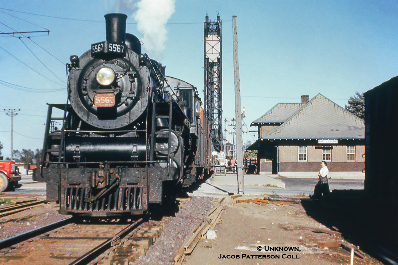 In response to Arnold’s 1975 image facing west, I offer this 1955 view facing east.  CNR K-3-a Pacific 5567 leads train M219, the evening Fort Erie-Stratford mixed, on its 114.9-mile journey home.  Baggage carts are positioned at the ready with the handler at work.  The stop at Port Colborne is scheduled as 1655h.  Trains M218/M219 operated daily except Sunday running Stratford-Brantford-Fort Erie, departing Stratford at 0715h arriving Fort Erie at 1225h, and returning from Fort Erie at 1615h to Stratford at 2125h, each train laying over at Brantford for about 45-50 minutes to meet mainline trains.  CNR 5567, a Grand Trunk Railway product of 1912, originally P4 class number 231, renumbered in 1923 to 5567, would be scrapped in May 1958.  Welland Canal bridge 20 (built 1929 for the 4th canal) stands tall in the background as it did for 68 years until removal in 1997.  Bridge 21 (Clarence Street) remains in service immediately to the south (92 years of service at this writing).  The small swing bridge over the 3rd canal, just this side of the lift bridge, remains locked in place as it has since 1929.At left overhead wires of the Niagara St. Catherines & Toronto Railway can be seen which were used by the interurban line to access the CN station until the end of passenger service on March 29, 1959.  Prior to the end of NS&T electric operations in 1960, an electric freight motor and wooden CN van (NS&T being part of Canadian National Electric Lines) were kept about a block and a half west (just west of Elm Street) to service the Robin Hood Mill just north of town.  Also note the quantity of semaphore signals for train orders, the Welland Canal bridge, and the junction with the Humberstone Subdivision on the east side of the canal.  Immediately below the lowest semaphore the roof of the water tower can be seen.  To the far right, a boxcar is seen spotted at the CN freight shed, removed during the 1960’s.  This spot later occupied by the local yard switcher when not in use, as seen in Arnold’s shot above.The third Grand Trunk/CNR station is seen at right, having opened in 1925 as a replacement for the 1880 GTR station, which was to be closed and demolished for the construction of the fourth Welland Canal.  The second station had sat on the site of the first, built circa 1853 by the Buffalo, Brantford and Goderich Railway.  Both the earlier stations were shared with the Welland Railway (crossing at diamond in photos).  Today the third station still stands as the Smokin’ Buddha restaurant with some other small tenants.Photographer Unknown, Jacob Patterson Collection slide.