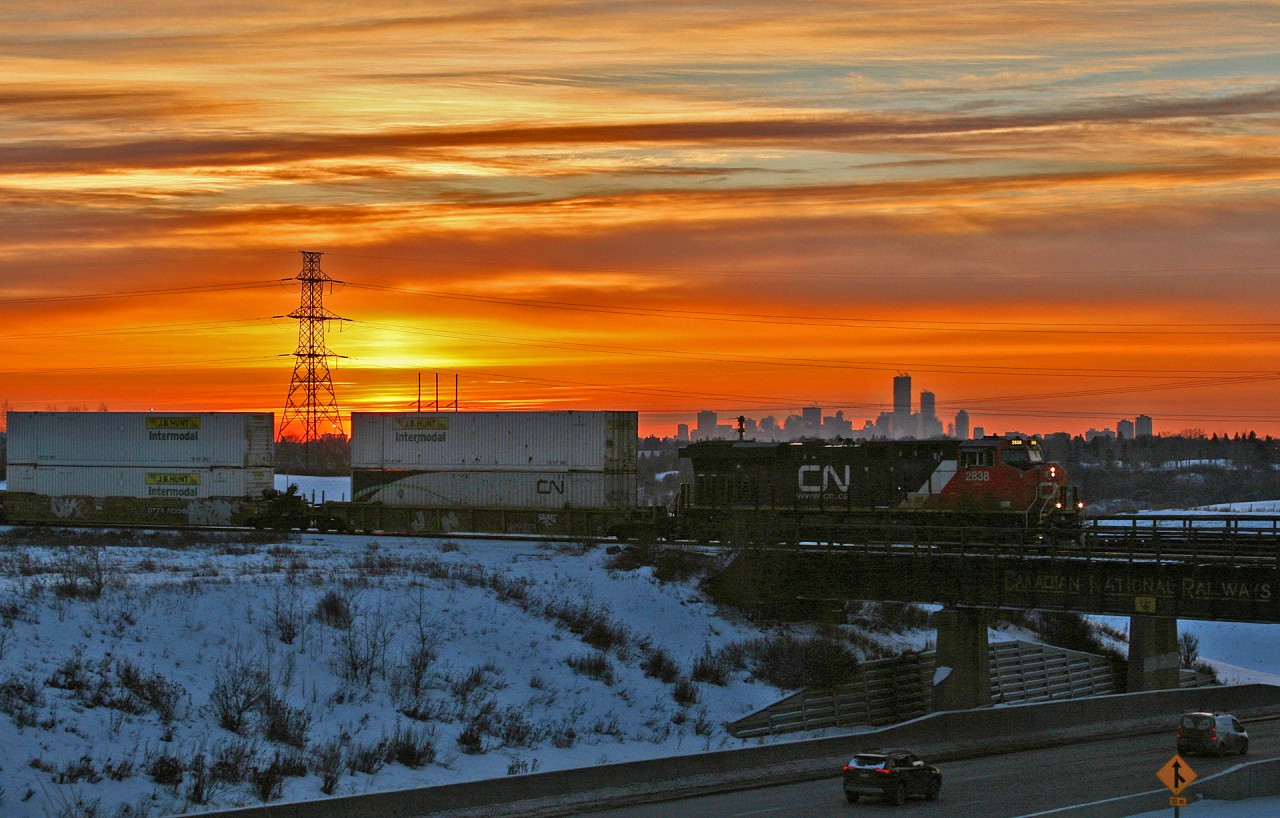Calgary to Winnipeg train Z 11451 03 rolls off the Camrose Sub with 113 platforms, as the February sun sets over the Edmonton city skyline.