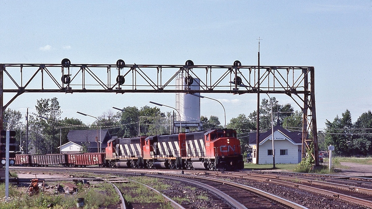 CN#450, North Bay to Mac, occupies the Quetton Street crossing on the Newmarket main and about to enter the Newmarket / Bala Subdivision switch.


   Powered by GP40-2L(W)'s   9562 / 9569 /  9422


  At Washago, July 4, 1982 Kodachrome by S.Danko


  Noteworthy


  Behind the station (beyond the Timing Circuit sign)  is the roadbed of the Northern Railway -  Muskoka branch,  Allandale Junction to Gravenhurst, opened 1873 to Washago and 1875 to Gravenhurst.


  That roadbed abandoned 1955 with the highway 11 Washago bypass construction that realigned the Newmarket parallel to the Bala to the new grade separation


  More Washago:
 

   station view