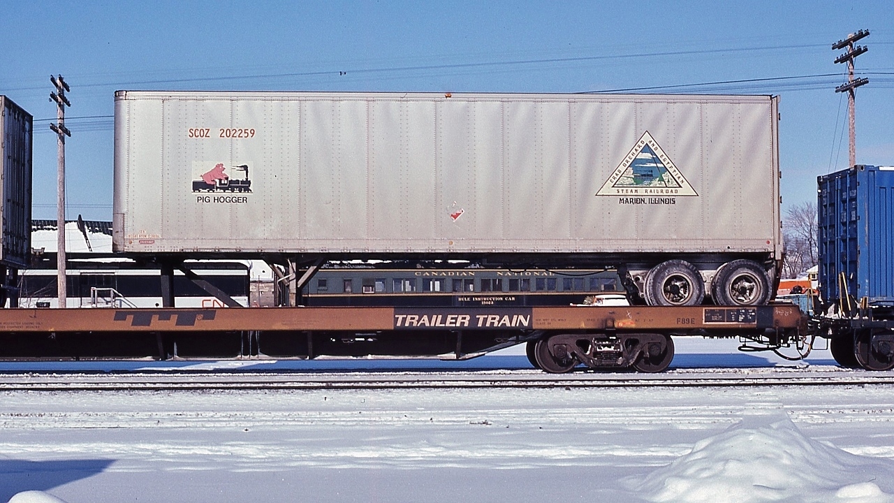 CRAB ORCHARD AND EGYPTIAN STEAM RAILROAD  “ PIG HOGGER “  SCOZ 202259 aboard a  TTX flat, 


 in the consist of  CN 2335 West  at London, January 17, 1981 Kodachrome by S.Danko


 Notable: CRAB ORCHARD and EGYPTIAN RAILROAD  -  AAR reporting SCOZ: the last steam powered common carrier ( freight only )


 Canadian connection:  the COER steam motive power ( second ) being 1940 built  CLC  ex Roberval & Saguenay #17 , a  2-8-0 in  COER service 1979 until 1986 when mechanical issue sidelined #17, then sold to Boon & Scenic Valley Railroad. ( thank you Donald R. McQueen: Constructed in Kingston )


 SCOZ owned 600 of those highway trailers and a handful of boxcars and 200 trailer flats


 COER remains a common carrier today with SW first generation power.


In the background:


 CN#15023 Rule Inspection Car  (ex CN Colonist Car #2719, nee Pullman 'ORVISTON' );  the 1991 Trackside Guide records Diesel Instruction Car #15023 as 'unserviceable' pending repair or retirement. 


 sdfourty