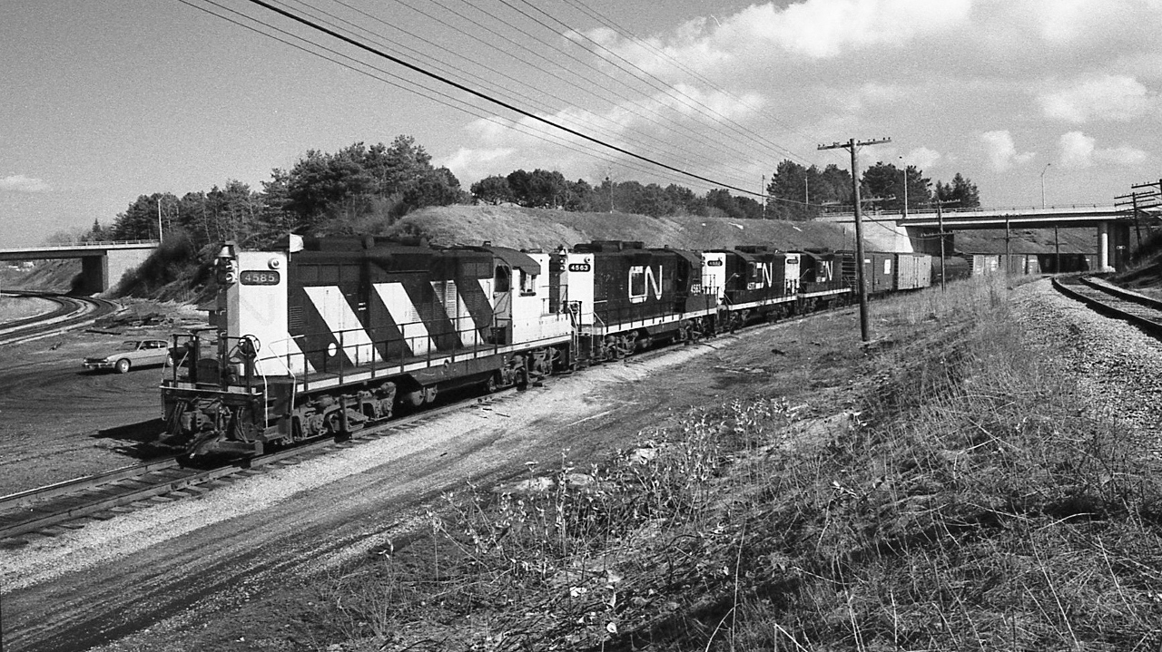 Approach to Hamilton West on the wye connecting track ( aka 'cow path' )


   Extra 4585 West  -   GeeP  9   quartette   -   4585 / 4563 / 4577 / 4561


  March 19, 1978 Kodak Tri X negative by S.Danko


   Notable: the location, the wye, from mile 37.3 Oakville Sub to mile 0.4 Dundas Sub ( let me know if I got this):
   
   to my left (out of view ) is the searchlight absolute signal governing westbound access to mile 0.4 Dundas Sub 
   
   over my left shoulder ( out of view) about 150 feet is the Hamilton West Junction wye switch to the south track Dundas Sub ( and beyond that the crossover to the north track); 

   to the left the Dundas Sub continues under the road bridge and beyond to Bayview Junction; 

   extra 4585 West train occupies the wye connecting track, and to the right, beyond the road bridge is Hamilton Junction; 

   to the extreme right and behind me is the CP Rail Goderich Subdivision ( approximately mile one), circa 1978,  and beyond the road bridge interchanges with CN at Hamilton Junction 


  the beauty of a 'true' 28mm lens ! 


  sdfourty