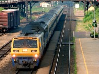 A westbound VIA train of conventional coaches speeds through Woodstock station led by LRC 6909 and a B unit.  There are boxcars in the small yard, a semaphore train order signal and the old Bay Street bridge.  The station is still there, but everything else has gone.

