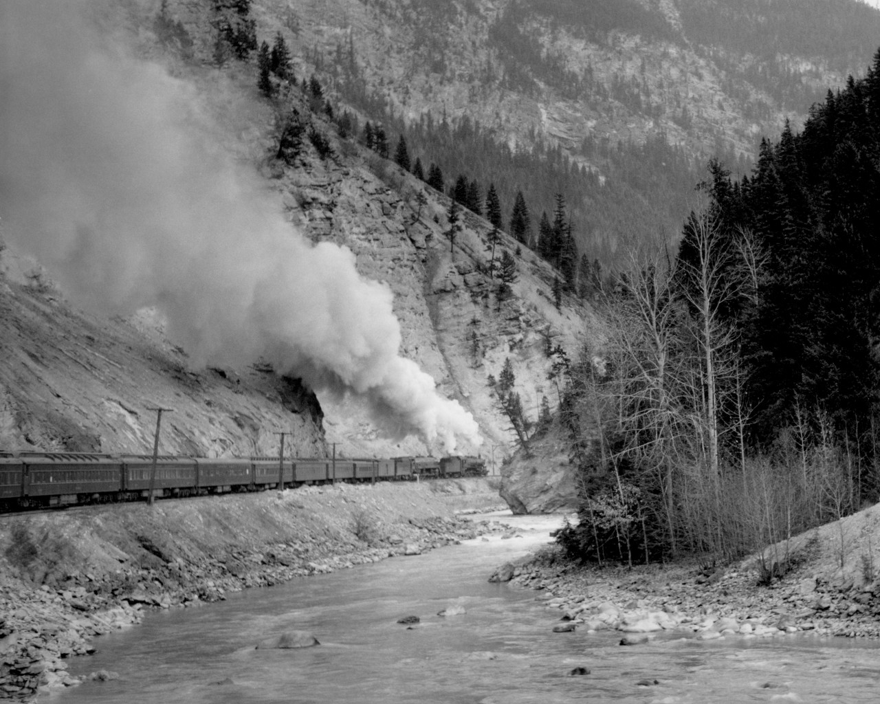Train no. 4 with R class helper and T1b road engine west of Leanchoil in lower Kicking Horse canyon.  Engine numbers unknown.