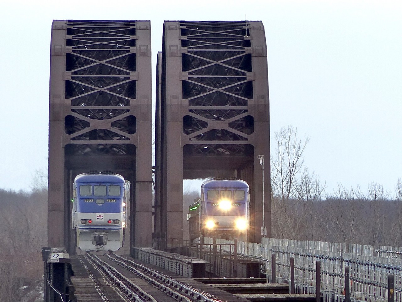 EXO train number 81 returns from its trio to Candiac while EXO 85 is heading there. The EMD F59PHI is the engine used for this line as both trains have them pushing/pulling. We see them crossing the CP LaSalle Bridge over the Saint-Lawrence river.