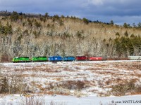 Through the winter countryside, NBSR westbound train 907 has a colorful lashup as they haul their train heading to McAdam and into Maine. 