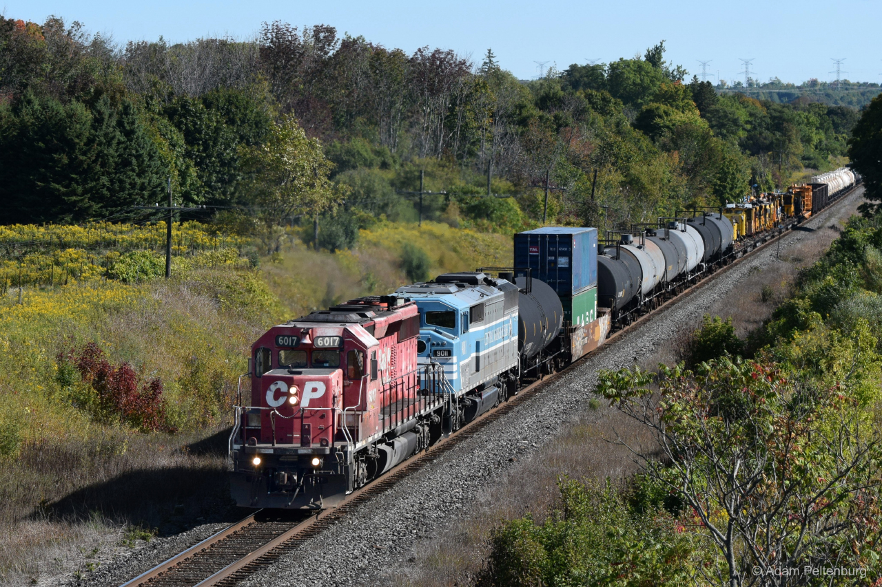 There's a story behind every photograph, and the one behind this photo of mine never ceases to get a laugh out of me. I was at Newtonville Road with my buddy Cam, not expecting to see much but we stuck around for most of the day just in case. Cam looks at his phone, and reads a message from his friend in Cobourg saying there's an SD40-2 leader heading our way. The thing about this spot is getting from one bridge to the other, CN to CP and vice versa, requires a fair bit of walking (or running). We were camped out at the CN bridge, and against our better judgement we chose to wait there thinking this train was further away. Spoiler alert: it wasn't. Within five minutes Cam turns away and goes silent, then yells "Hey, I think I see it!". Of course, if Cam can see the train from here, it's already pretty close. We're both running at full speed to get to the other bridge in time. Not even halfway there and we hear it blow the horn for the Lancaster Road grade crossing, and only now do we realize how close it is and that we might not make it in time. Somehow, we managed to get there just before it crossed the tree line and we were able to snap a few photos before it passed us. This train came with Central Maine & Quebec 9011, an SD40-2F of CP heritage, trailing second. Throughout 2020, these engines made appearances all over Ontario. As the former CMQ track was being upgraded to CP standards, ballast trains were regularly going back and forth between there and Sudbury. This is one of those trains, swelled with several other freight cars and MOW equipment it picked up in Smiths Falls. Having missed out on seeing these locomotives pull mainline trains ten or more years ago, it was nice getting this chance to capture them in action.