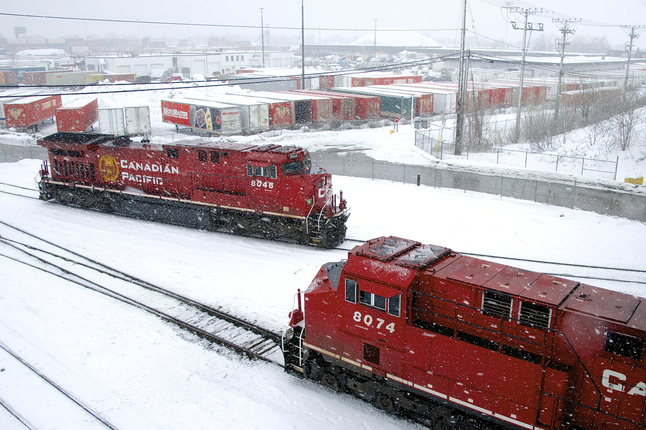 On a snowy morning, CP 112's mid-train DPU (CP 8046) is temporarily tied down at left, as the head end power shoves a last cut of intermodal cars into Lachine IMS Yard.