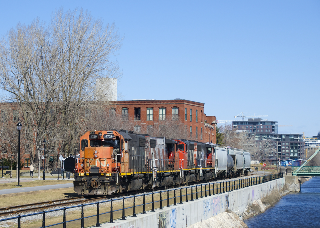 The Pointe St-Charles Switcher has a GP38-2, A GP38-2W and two GP40-2L(W)'s (CN 4729, CN 4774, CN 9576 & CN 9523) as it backs up towards Ardent Mills to pick up grain empties. It has come straight from the Port of Montreal and so has four cars picked up there. A crewmember enthusiastically waves from the lead unit.