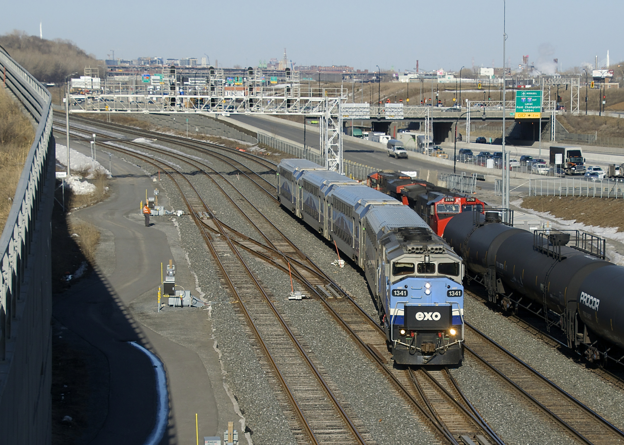 A crewmember watches on as EXO 1207 passes CN 306 at Turcot Ouest, which is stopped and changing crews.