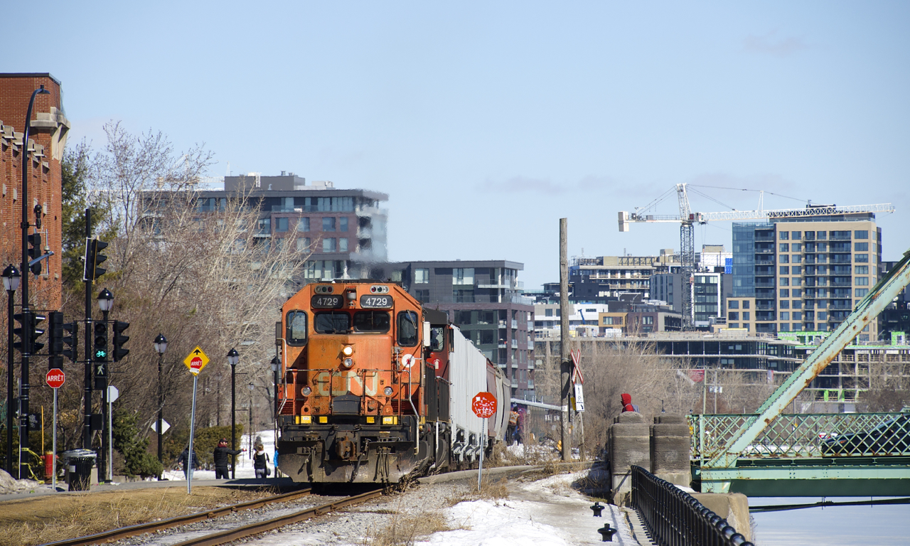 The Pointe St-Charles switcher is crossing Charlevoix street with 6 grain cars for Ardent Mills. At left is a light for a new walking/bike path which parallels the East Side Canal Bank Spur.