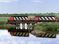 Grain spotter out of North Battleford to Spiritwood crosses a creek with a beaver dam below the pile trestle